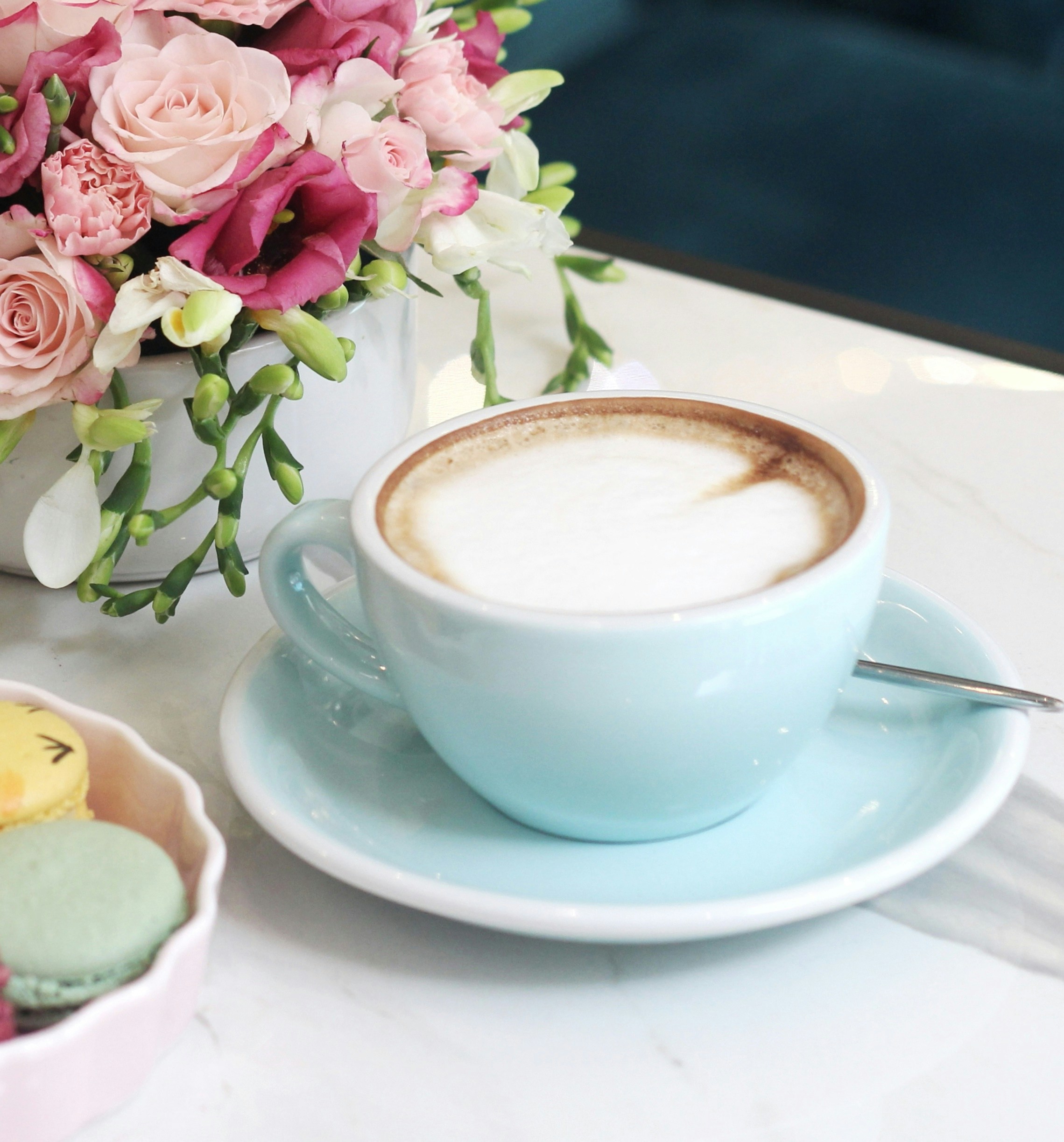 Cappuccino in a blue cup with macarons and flowers